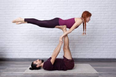 Genç çift evde farklı yerlerde akro yoga pozları vererek eğleniyor..