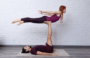 Genç çift evde farklı yerlerde akro yoga pozları vererek eğleniyor..