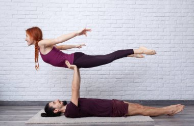 Genç çift evde farklı yerlerde akro yoga pozları vererek eğleniyor..