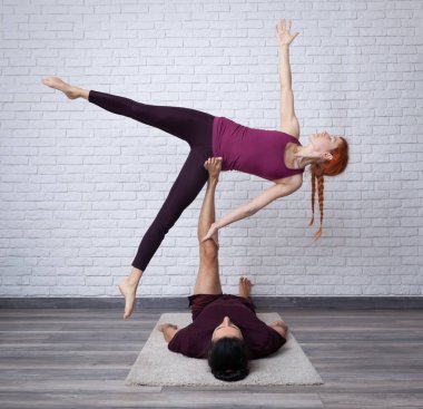 Genç çift evde farklı yerlerde akro yoga pozları vererek eğleniyor..