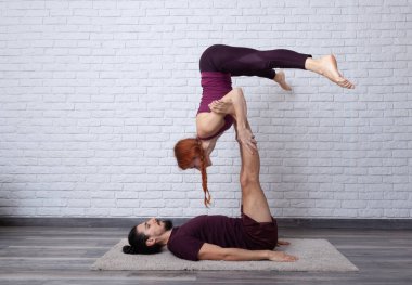 Genç çift evde farklı yerlerde akro yoga pozları vererek eğleniyor..
