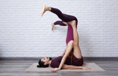 Genç çift evde farklı yerlerde akro yoga pozları vererek eğleniyor..