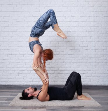 Genç çift evde farklı yerlerde akro yoga pozları vererek eğleniyor..