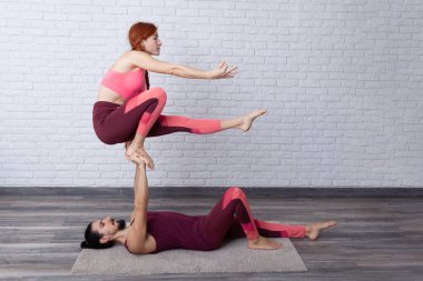 Genç çift evde farklı yerlerde akro yoga pozları vererek eğleniyor..