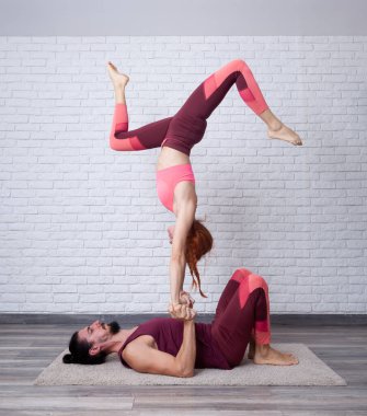 Genç çift evde eğleniyor. Akro-yogayla el ele oynuyorlar. Ayaklarıyla oynuyorlar..