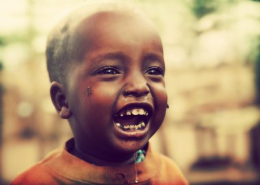 Poor young child laughing with tsetse insects on him. Tanzania, Africa clipart
