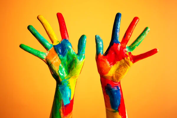 Mãos pintadas, diversão colorida. Fundo laranja — Fotografia de Stock