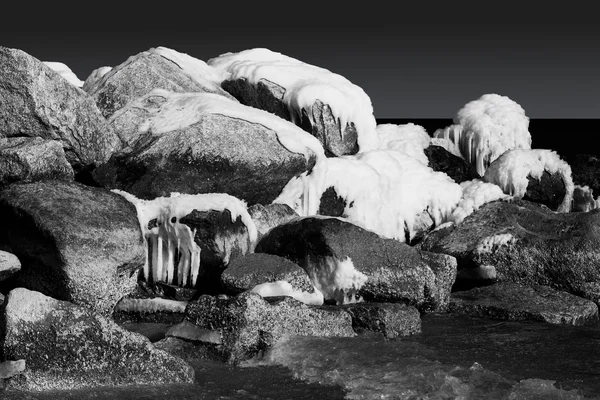 Schnee- und eisbedeckte Felsen im Meer. schwarz-weiß — Stockfoto