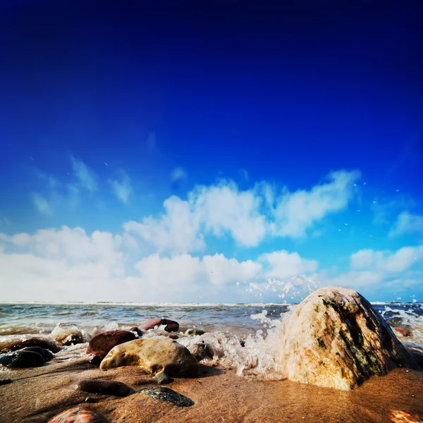 Ondas batendo pedras na praia ensolarada — Fotografia de Stock