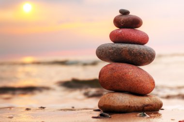 Stones pyramid on sand symbolizing zen, harmony, balance clipart