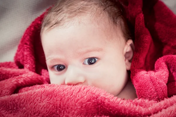 Precioso bebé de 3 meses acostado en la cama cubierto con manta roja . —  Fotos de Stock