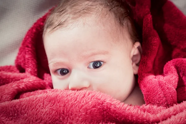 Lovely 3 months baby lying on bed covered with red blanket. — Stock Photo, Image