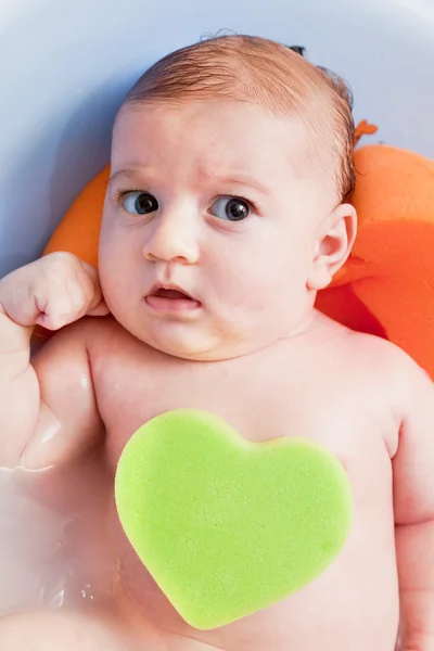Bathing a young 3 months baby with a heart shaped sponge — Stock Photo, Image