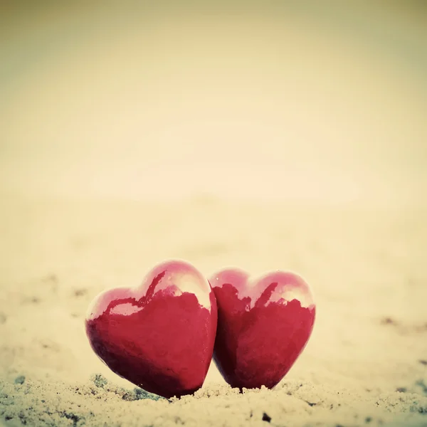 Two red hearts on the beach symbolizing love, Valentine's Day, romantic couple — Stock Photo, Image