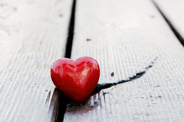 Coração vermelho em fenda de prancha de madeira. Símbolo do amor — Fotografia de Stock