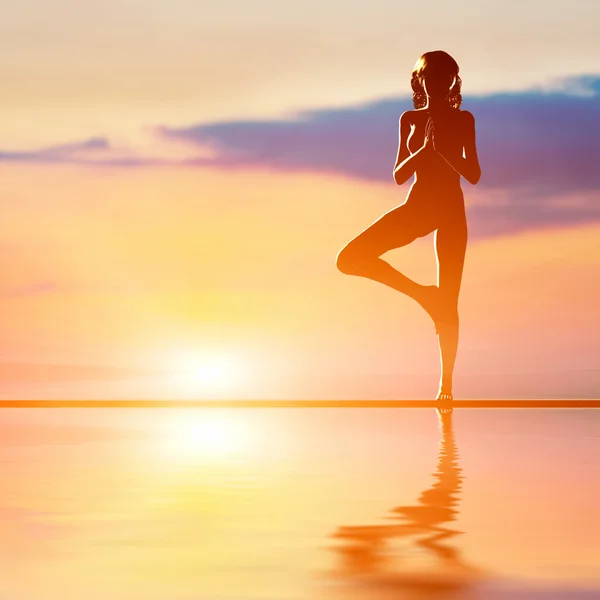 Una silueta de una mujer de pie en posición de yoga en el árbol —  Fotos de Stock