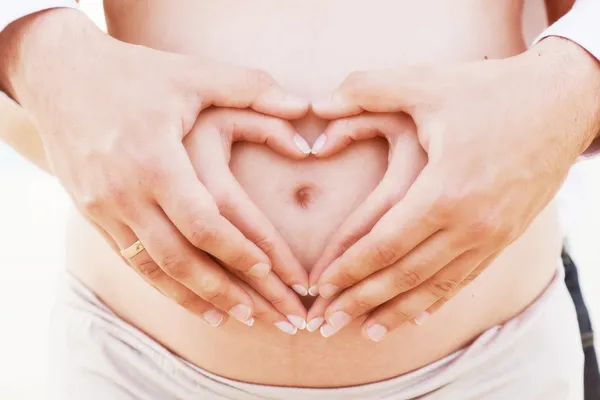 Heart shape on the pregnant belly Stock Photo