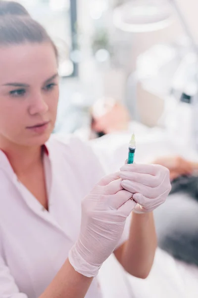 Aesthetic medicine doctor preparing syringe for injection in beauty salon