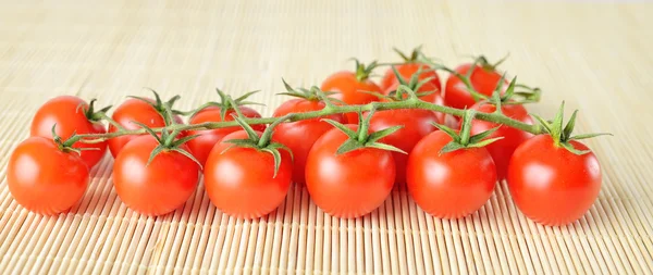 Panorama de tomates cherry frescos sobre fondo de bambú — Foto de Stock