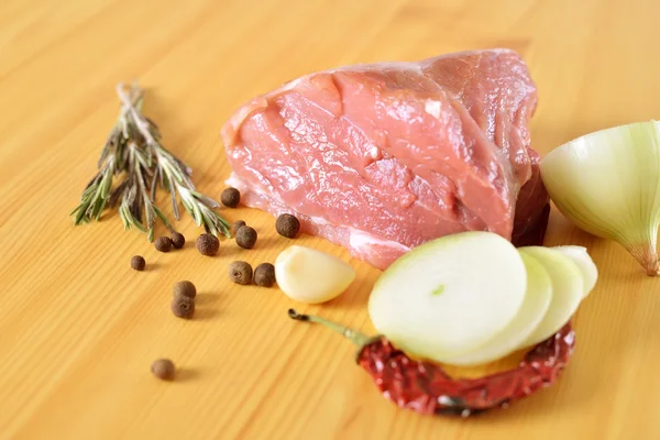 Fresh raw meat with spices, red chili pepper, onion and rosemary on the board