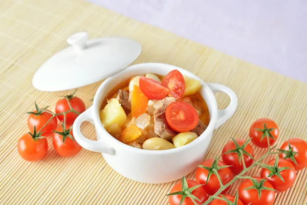 Een kom van gezonde aardappelsoep met wortel, tomaten en vlees Stockfoto