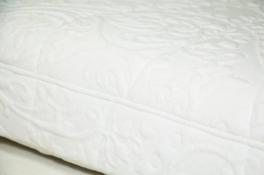 Yatağın arka planına yakın plan, desenli beyaz yatak kumaşı.