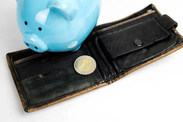 Una moneda de dos céntimos de euro sobre un fondo claro, junto a una cartera vacía y una alcancía. Crisis, impago, inflación. — Foto de Stock