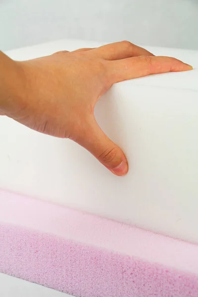 The hand presses on the surface of the rubber foam. Checking hardness and softness. Choosing the best type and quality. Close-up. Stock Picture