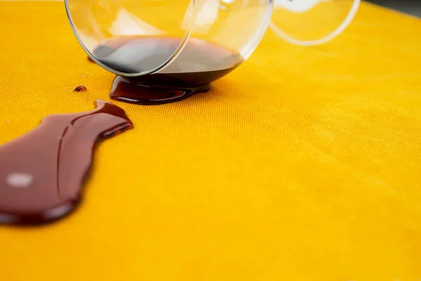 A spilled glass of wine on the tablecloth. Cleaning clothes and furniture from stains. Royaltyfria Stockbilder