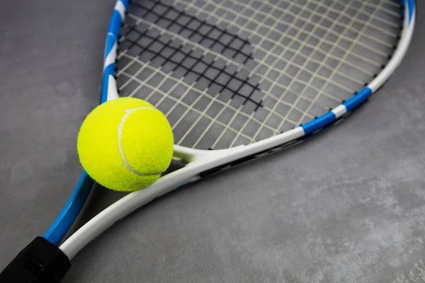 Tennisschläger und Ball auf grauem Hintergrund. Sportspiele. Die Meisterschaft. lizenzfreie Stockfotos