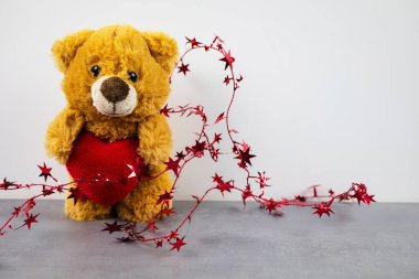 Oyuncak bebek kalp şeklinde bir yastığı sevgiyle tutuyor..