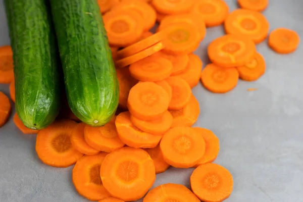 A set of vegetables, carrots, sliced into circles, and a whole cucumber