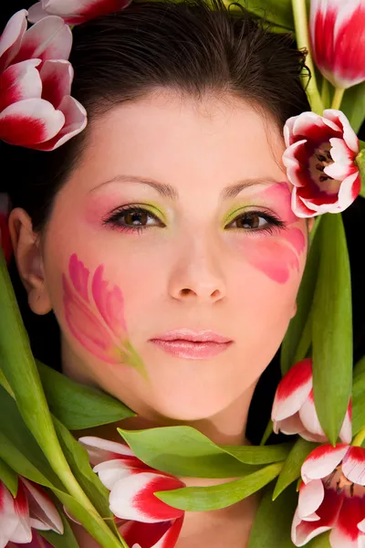 Zbliżenie twarzy kobieta oprawione tulipany — Zdjęcie stockowe