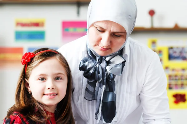 iki küçük kız öğrenciler sınıfta genç öğretmeni ile