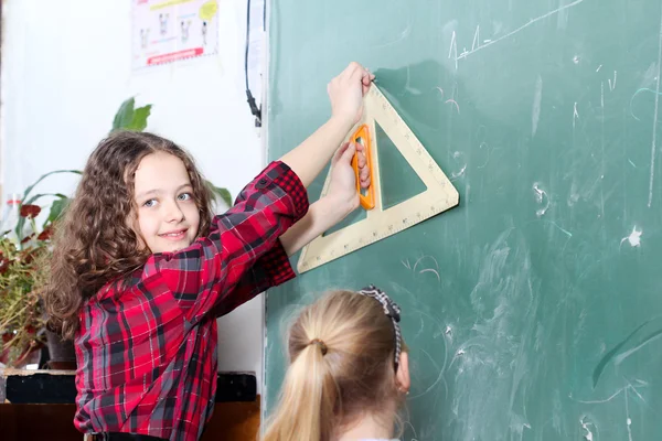 Liten skolflicka arbetar med triangel — Stockfoto