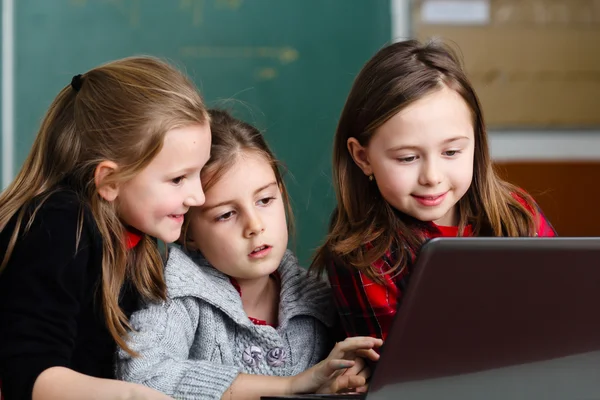 Schoolgirls working with laptop in classroom — Stock Photo, Image