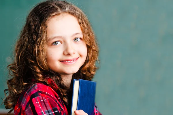 Bonita colegiala sosteniendo un libro — Foto de Stock