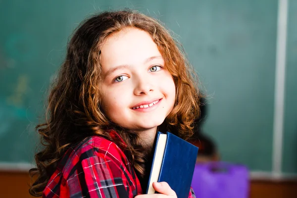 Söt skolflicka håller en bok — Stockfoto