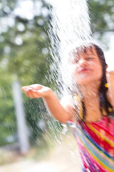 Menina feliz desfrutando no dia de verão e brincando com a água — Fotografia de Stock