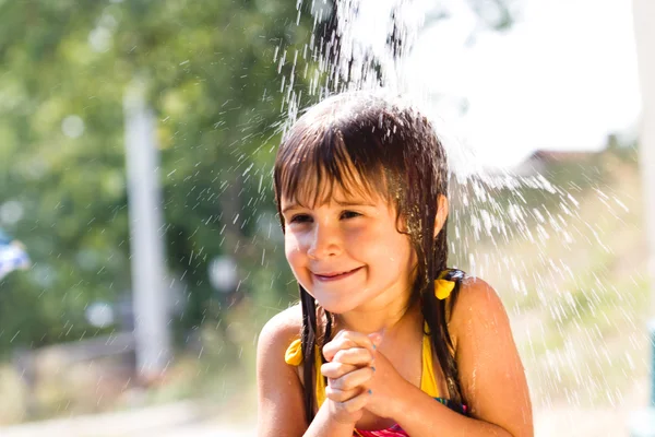 Menina feliz desfrutando no dia de verão e brincando com a água — Fotografia de Stock