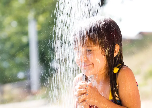 Glad liten tjej njuter i sommardag och leker med vatten — Stockfoto