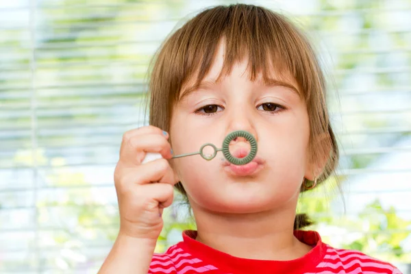 Beautiful little girl blowing soap bubbles indoor — Stock Photo, Image