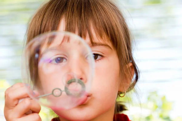Beautiful little girl blowing soap bubbles indoor — Stock Photo, Image