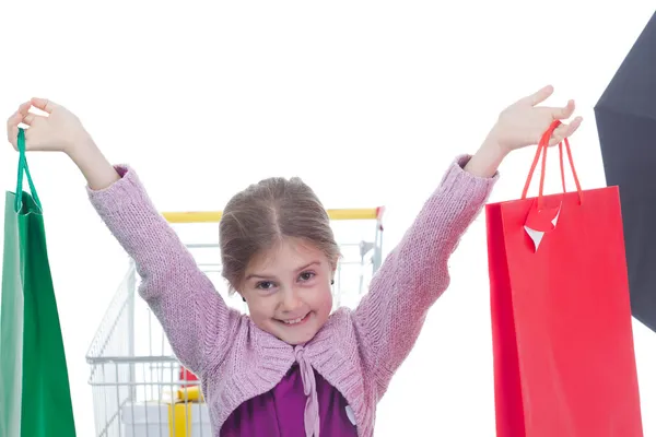 Little girl in shopping with shopping cart and coloured bags — Stock Photo, Image