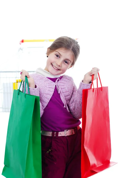 Little girl in shopping with shopping cart and coloured bags — Stock Photo, Image