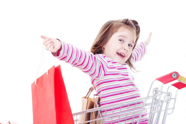 Little girl sitting in a cart with colorful bags — Stock Photo, Image
