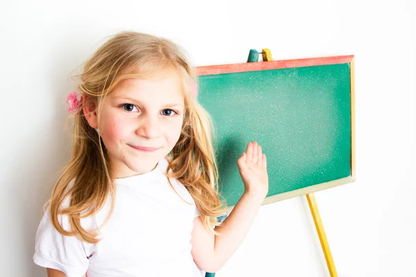 Šťastný školačka pózuje před tabulí — Stock fotografie