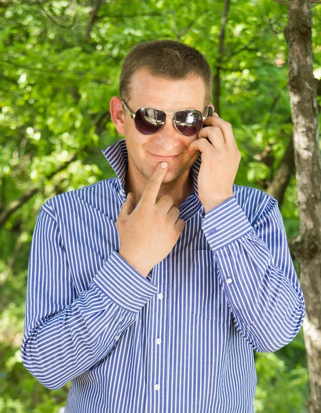 젊은 남자는 녹색 숲을 걷는 동안 전화를 사용 하 여 — 스톡 사진