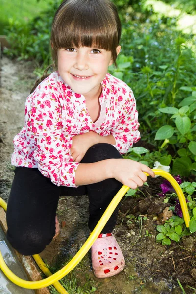 Klein meisje spelen met slang en water — Stockfoto