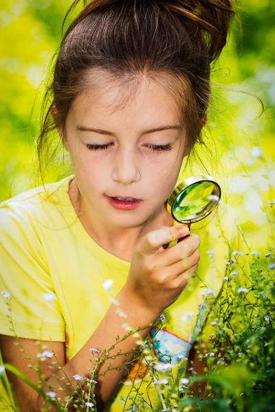 Çiçeklere bakarak büyüteç ile kız